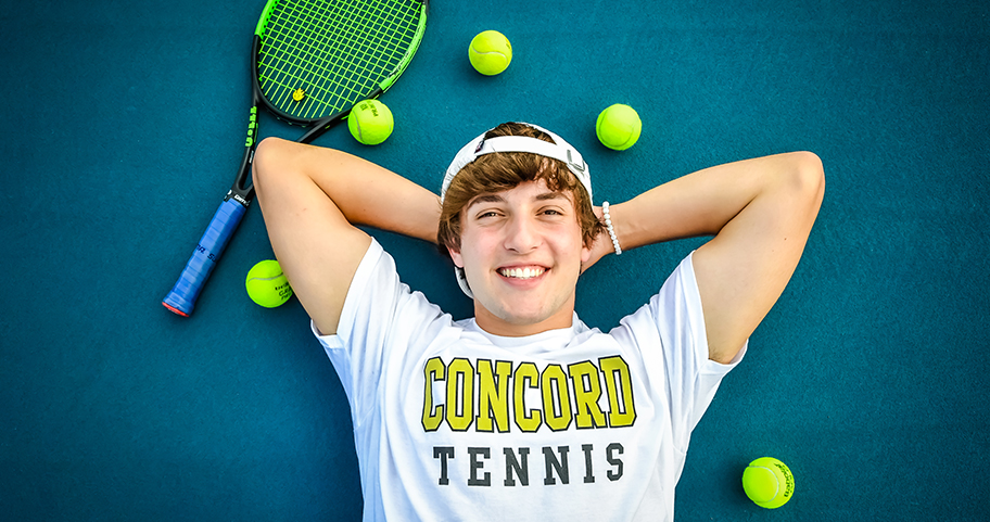 A young person laying on a tennis court smiling