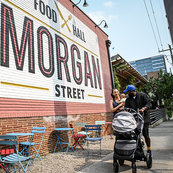 A family walks past a food hall on Morgan Street in downtown Raleigh.