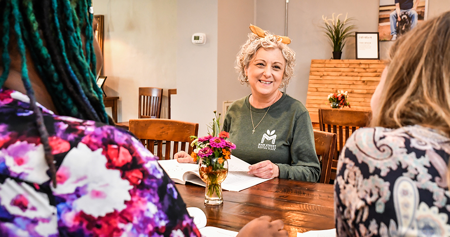 A woman smiling at two women across the table