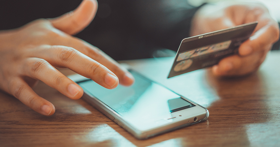 Person using a phone and their credit card.