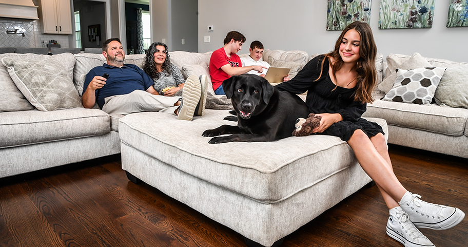 A family sits on a sectional sofa in their home