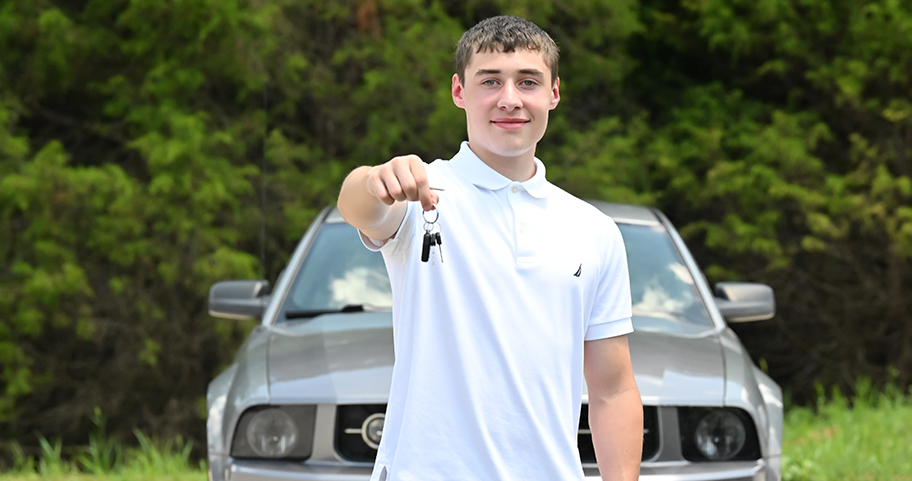 Young male driver showing off his keys and new car