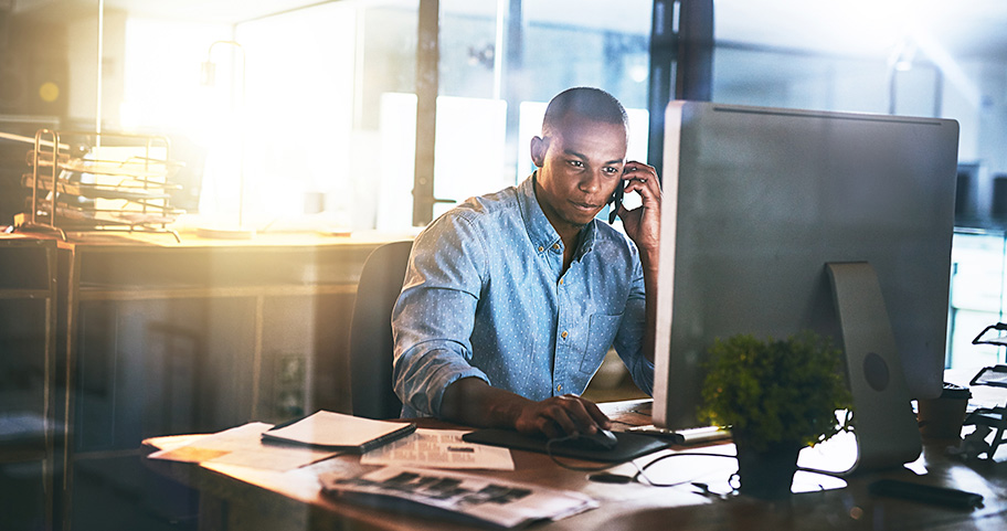 Person sitting behind a computer on the phone.