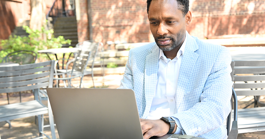 Man using a laptop outside in a seating area