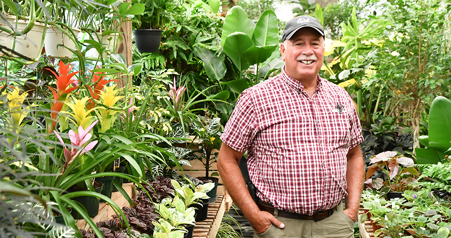 Man stands in front of tropical plants  
