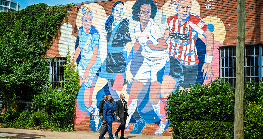 A group of businessmen walking outside near a large mural.