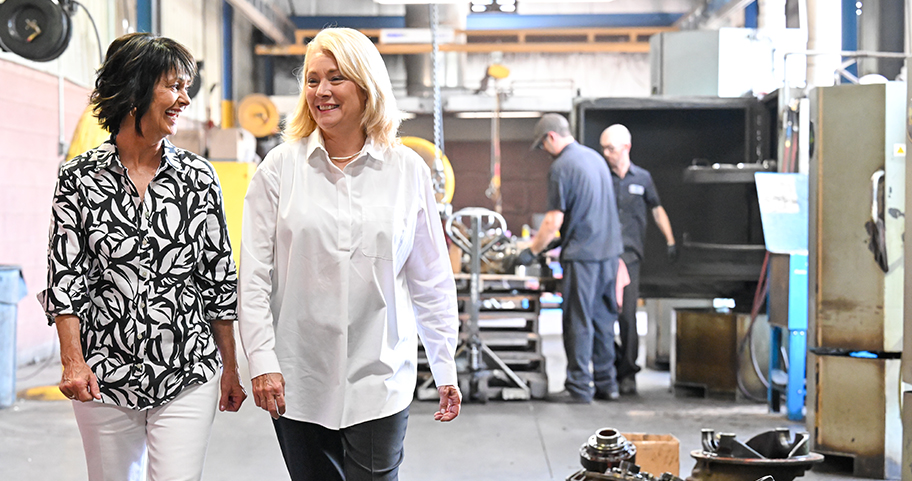 Two women walking together wile talking in a car shop