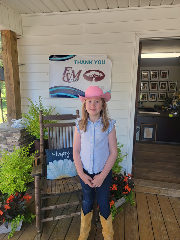 A young girl wearing a pink cowgirl hat outside of Wings of Eagles Ranch