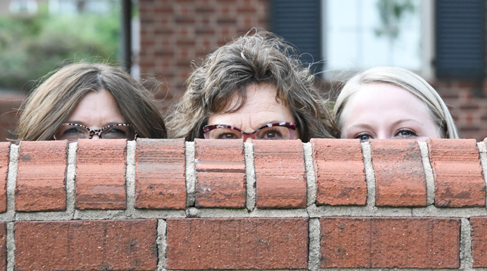 People having fun peeking from behind a brick wall.