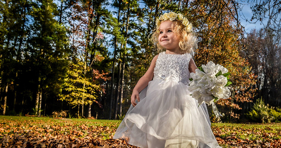 A young girl wearing a fancy dress and holding a bouquet