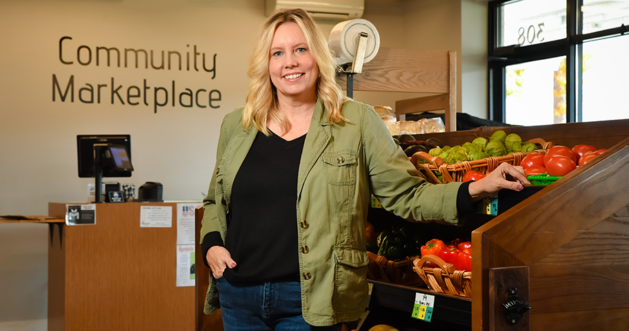 A woman standing next to produce at the Community Marketplace 