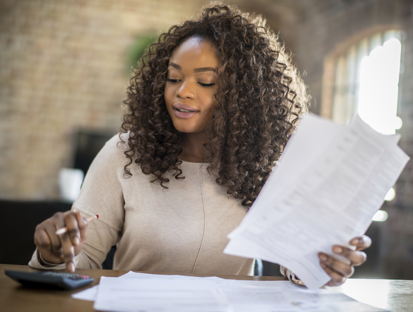 A person reviewing paperwork and using a calculator.