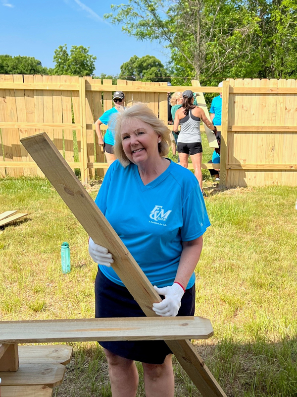 F&M teammate having fun holding a board for the fence