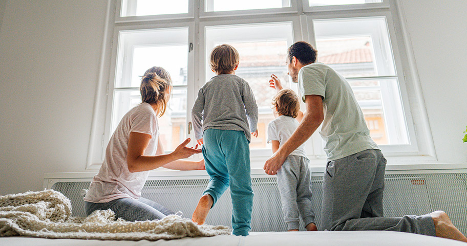 Family sitting on bed looking out the bedroom window.