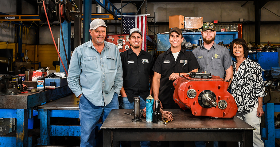 Local mechanic shop employees standing in their shop smiling 