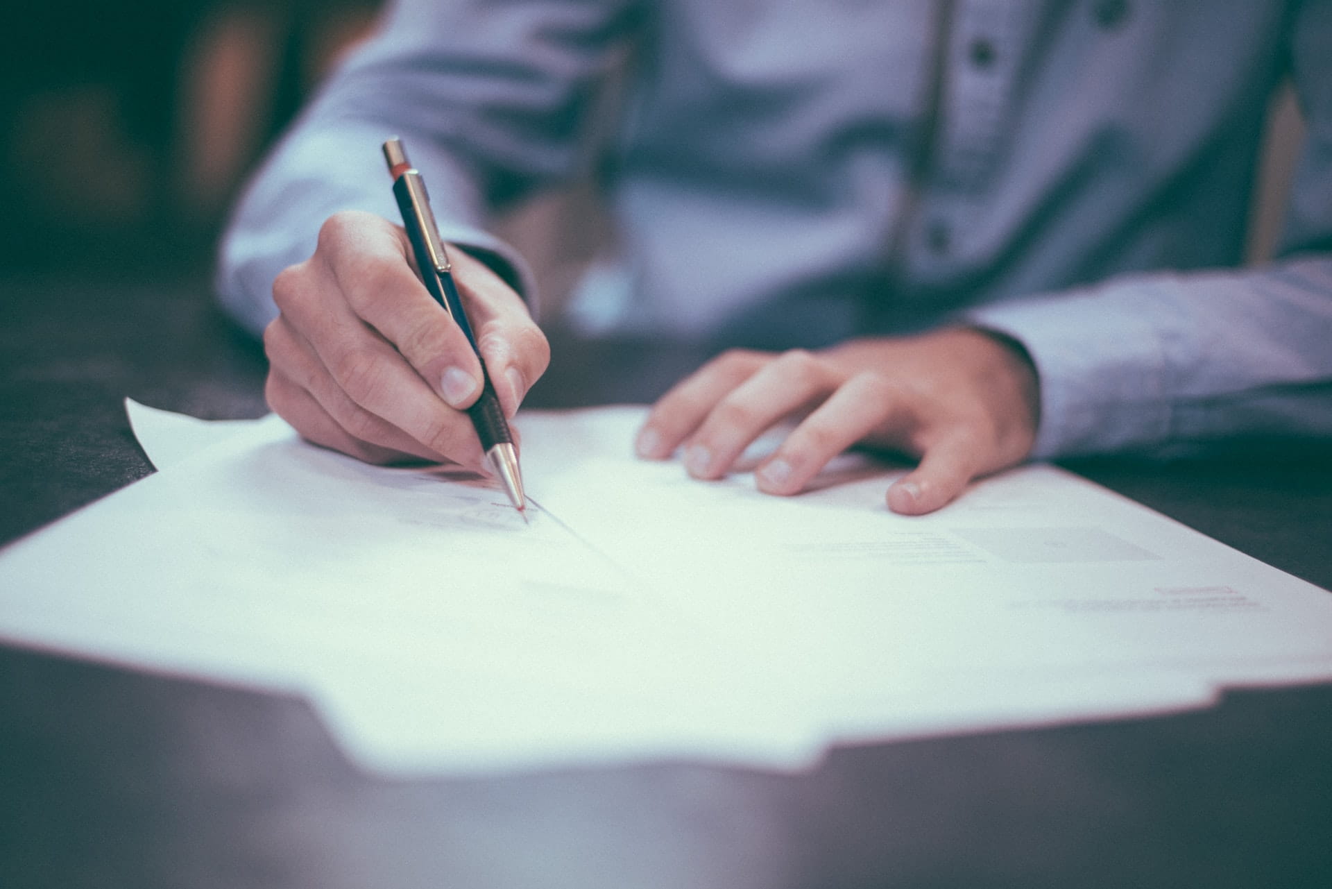 Person signing documents for their business loan.