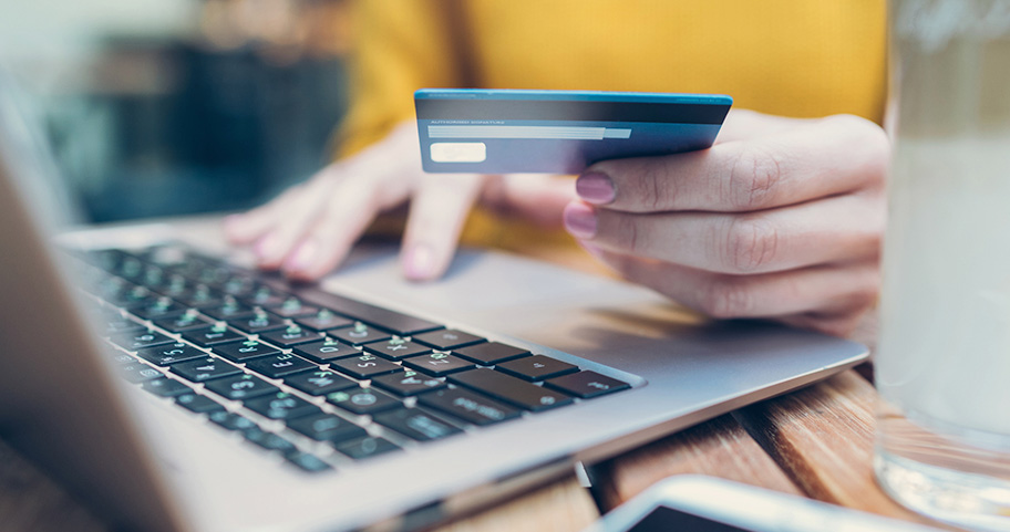 Person holding a credit card while shopping online.