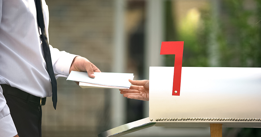 A hand coming out of a mailbox to grab a check.