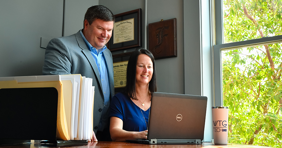 Two business people working on their laptop at an office.