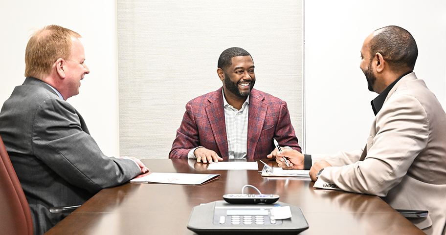 A F&M Bank employee sits with clients at a conference desk 