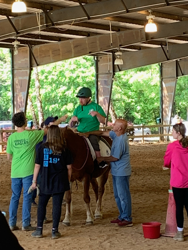 A participant in the Wings of Eagles Ranch therapeutic horseback riding program sitting on a horse