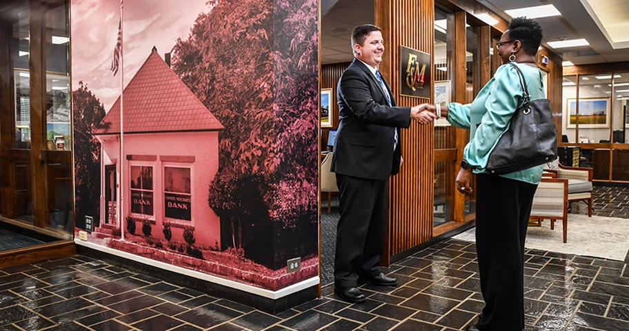 A F&M Bank employee shakes hands with a client in a local office