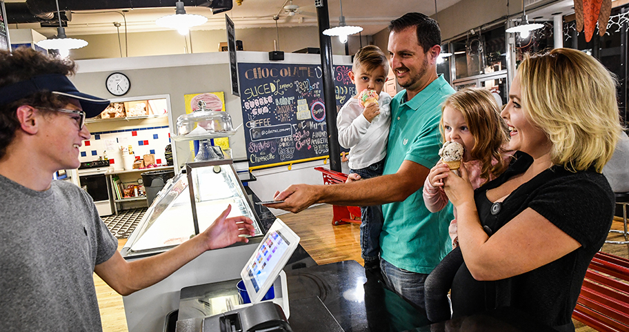 A father paying for ice cream for his family with his debit card.