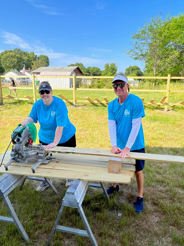 F&M Bank teammates use a saw to cut materials for a fence