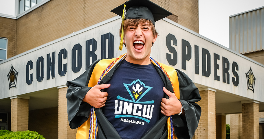 A high school graduate shows off his new college t-shirt   